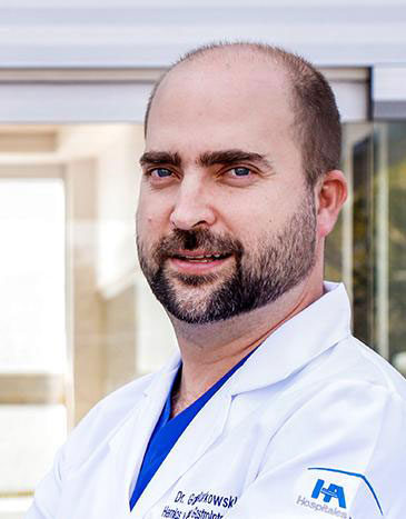 Es la foto de perfil de un cirujano general especialista en gastrocirugía en Guadalajara de Hospital Angeles Del Carmen. Utiliza una bata blanca, barba y es de tez blanca. 