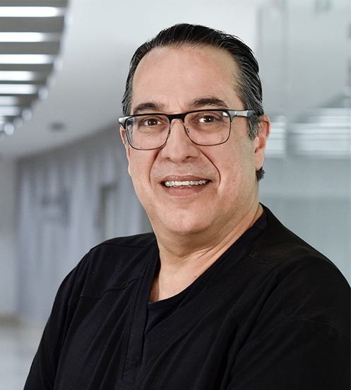 Es la foto de perfil de un cirujano neurológico en Huixquilucan de Hospital Angeles Lomas. Usa un uniforme negro, tiene lentes, es de tez morena y de cabello oscuro.