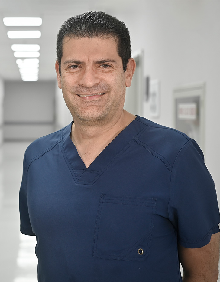 Es la foto de perfil de un ginecólogo y obstetra en Ciudad de México de Hospital Angeles Universidad. Usa un uniforme médico azul marino. Tiene el cabello negro y los brazos cruzados por detrás.