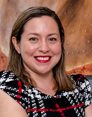 Es la foto de perfil de una oncóloga médica en León de Hospital Angeles León. Usa una blusa negra con rayas blancas y cuadros blancos. Tiene el cabello a los hombros y está sonriendo amablemente.