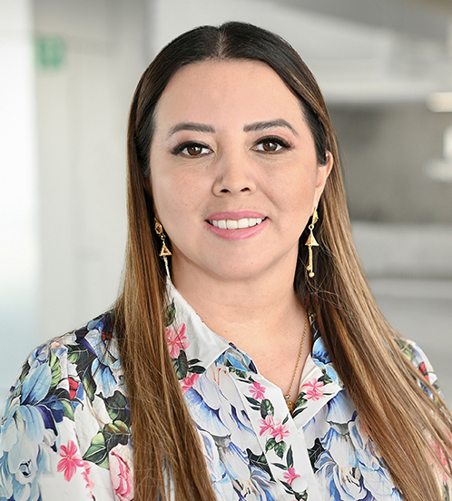 Es la foto de perfil de una ginecóloga y obstetra en Querétaro de Hospital Angeles Centro Sur. Blusa blanca con flores azules y rosas, tiene el cabello largo.