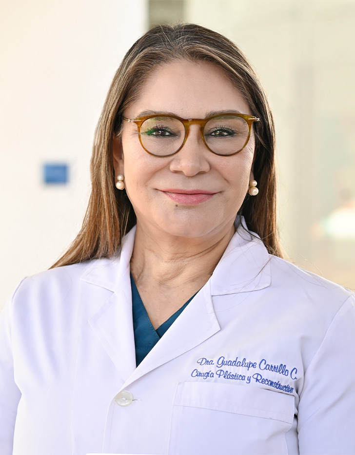Es la foto de perfil de una cirujana de mano y cirujana plástica en Tijuana de Hospital Angeles Tijuana. Usa bata blanca y lentes. Tie el cabello castaño y lacio.