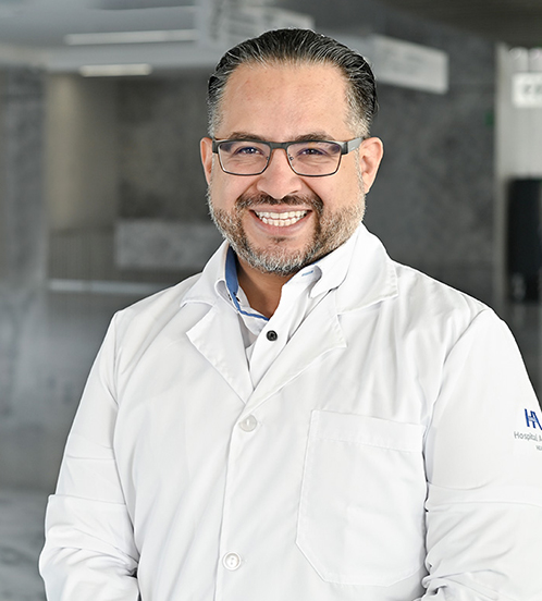 Es la foto de perfil de un cirujano general en Querétaro de Hospital Angeles Centro Sur. Viste un uniforme negro, un reloj y usa lentes.