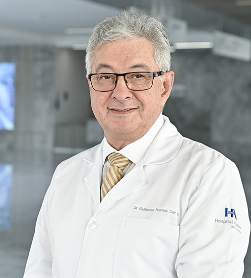 Es la foto de perfil de un pediatra en Querétaro de Hospital Angeles Centro Sur. Viste una bata blanca, camisa blanca y una corbata blanca, tiene lentes y el cabello canoso.