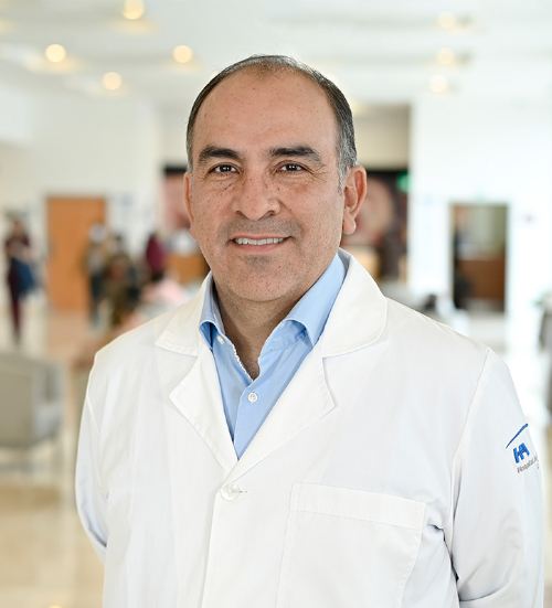 Es la foto de perfil de un cardiólogo en Xalapa de Hospital Angeles Xalapa. Usa una bata blanca con una camisa azul claro y corbata roja. Tiene el cabello negro y gris.