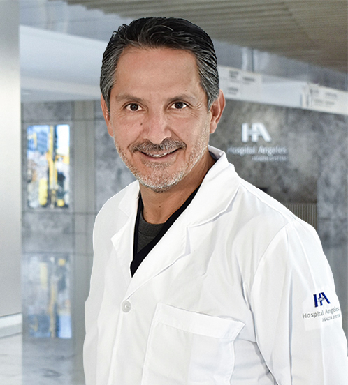 Es la foto de perfil de un urólogo en Querétaro de Hospital Angeles Centro Sur. Viste una bata blanca con una playera azul marino con rojo, tiene barba y está sonriendo.