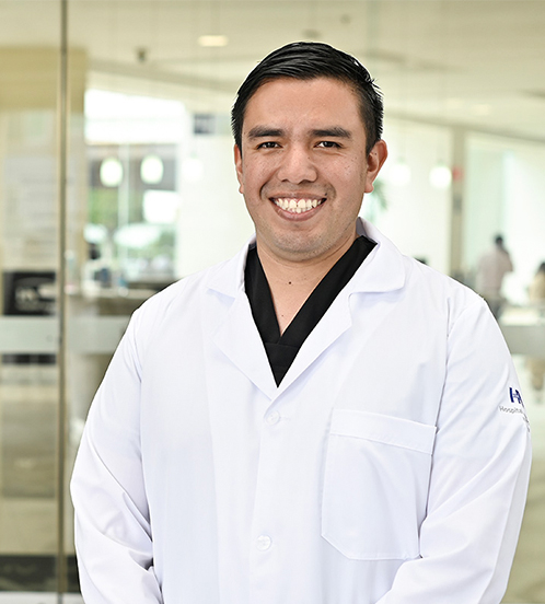 Especialista en Ortopedia y Traumatología del Hospital Angeles Acoxpa Ciudad de México. Usa una bata blanca con un uniforme médico negro. Tiene el cabello negro y la ceja poblada.