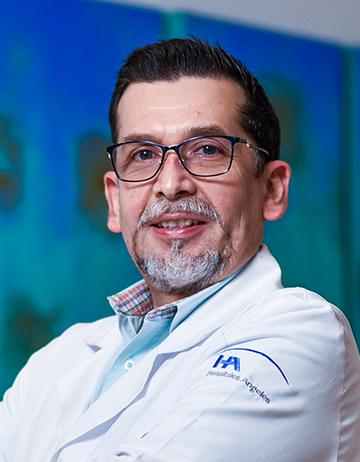 Es la foto de perfil de un reumatólogo en Villahermosa de Hospital Angeles Villahermosa. Usa una bata blanca y camisa azul claro. Tiene el cabello negro y usa lentes.