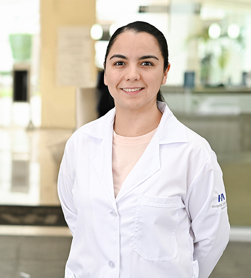 Es la foto de perfil de una cirujana oncóloga en Ciudad de México de Hospital Angeles Acoxpa. Usa una baya blanca con una blusa rosa palo. Tiene los brazos cruzdos atras y el pelo recogido. Está sonriendo.