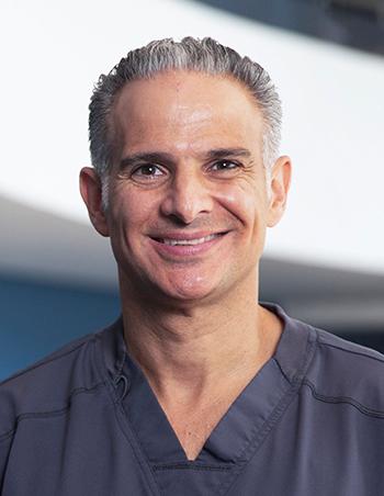 Es la foto de perfil de un oftalmólogo en Huixquilucan de Hospital Angeles Lomas. El doctor usa uniforme gris, tiene el cabello canoso y está sonriendo.