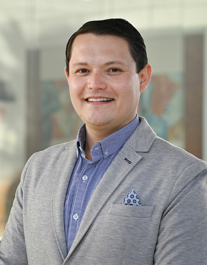Es la foto de perfil de un ortopedista, traumatólogo y artoscopista en Tijuana de Hospital Angeles Tijuana. Usa un saco color gris y una camisa azul. Tiene el cabello negro.
