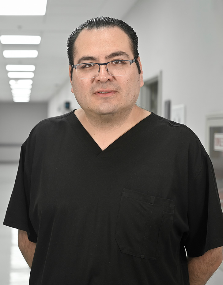 Es la foto de perfil de un cirujano general en Ciudad de México de Hospital Angeles Universidad. Usa un uniformr médico negro y lentes.  Tiene el cabello negro.