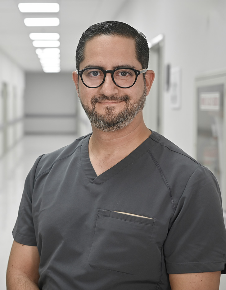Es la foto de perfil de un cardiólogo en Huixquilucan de Hospital Angeles Lomas. El doctor usa un uniforme gris, tiene lentes y cabello oscuro..