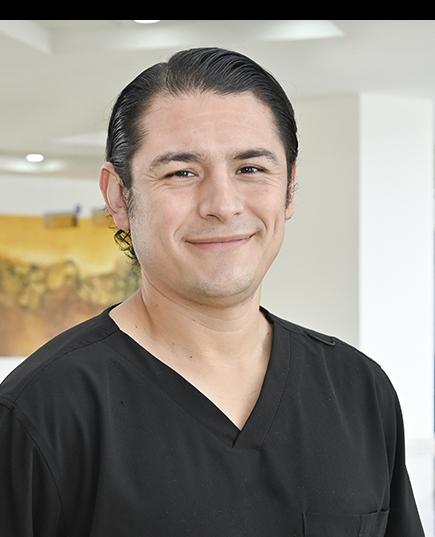 Es la foto de perfil de un nefrólogo y médico interno en Ciudad Juárez de Hospital Angeles Ciudad Juárez. Viste un uniforme negro y está sonriendo suavemente. 