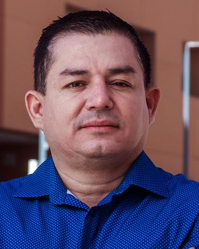 Es la foto de perfil de un cirujano general en Torreón de Hospital Angeles Torreón. Usa una camisa azul. Tiene elcabello negro. Sonrie ligeramente.