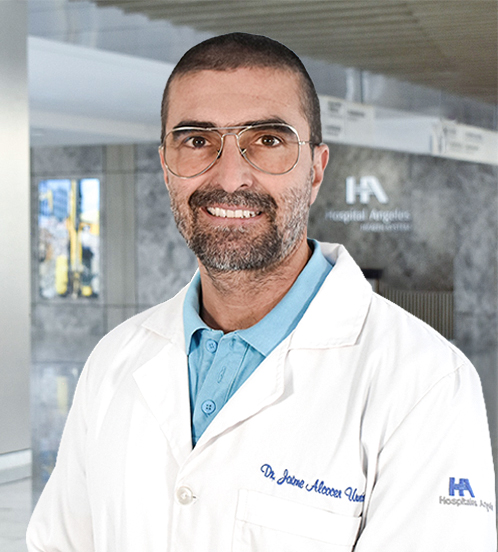 Es la foto de perfil de un ginecólogo y obstetra en Querétaro de Hospital Angeles Centro-sur. Usa una bata blanca con un uniforme médico color azul claro. Tiene el cabello color café y la barba café con gris.