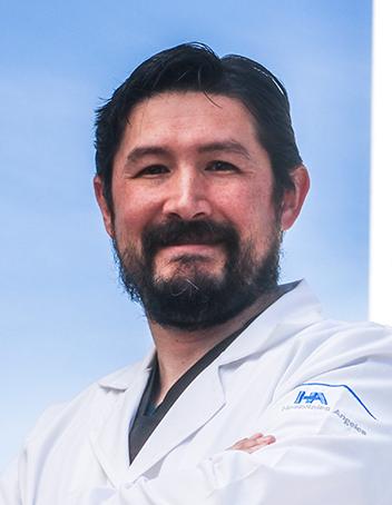 Es la foto de perfil de un cirujano maxilofacial en Torreón de Hospital Angeles Torreón. Usa una bata blanca. Tiene el cabello y barba negro.