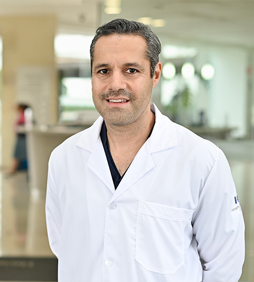 Es la foto de perfil de un ginecólogo y obstetra en Huixquilucan de Hospital Angeles Lomas. El doctor usa un uniforme negro con cuello V, es de cabello oscuro, tiene barba canosa y tez blanca.