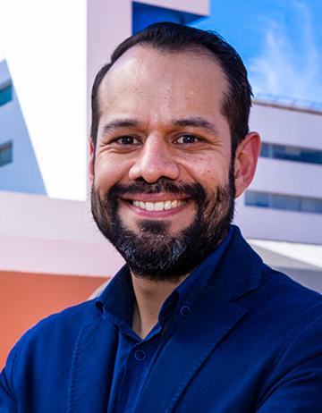 Es la foto de perfil de un neumólogo pediátrico y pediatra en Tijuana de Hospital Angeles Tijuana. Usa un saco y camisa azul marino. Tiene el cabello y barba negro. Está sonriendo