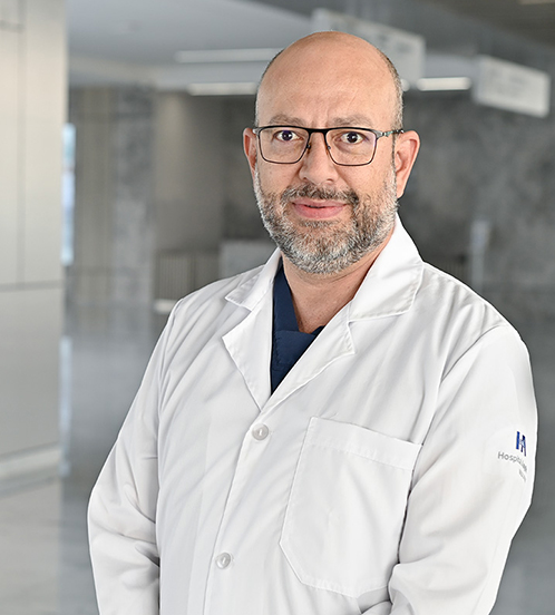 Es la foto de perfil de un urólogo en Querétaro de Hospital Angeles Centro Sur. Usa un traje azul marino con rayas, una camisa blanca y una corbata rojo vino con cuadros blancos.