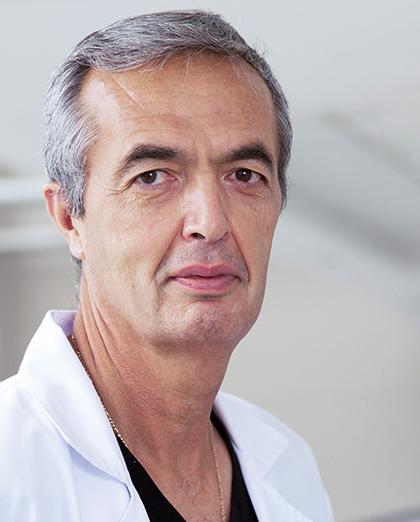 Es la foto de perfil de un ginecólogo y obstetra en Huixquilucan de Hospital Angeles Lomas. Tiene cabello canoso corto, tez apiñonada y una bata blanca.