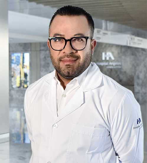 Es la foto de perfil de un radiooncólogo en Querétaro de Hospital Angeles Centro-sur. Tiene el cabello, barba y ojos color café. Sus lentes son negros. Usa una bata blanca al igual que su camisa.