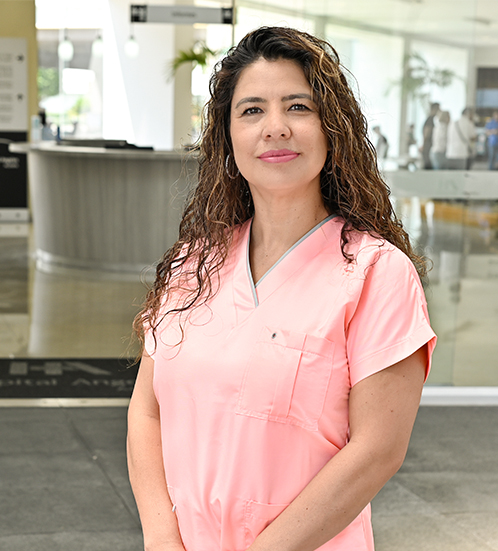 Es la foto de perfil de una ginecóloga y obstetra en Ciudad de México de Hospital Angeles Acoxpa. Usa un uniforme médico color rosa claro. Tien el cabello chino y castaño.