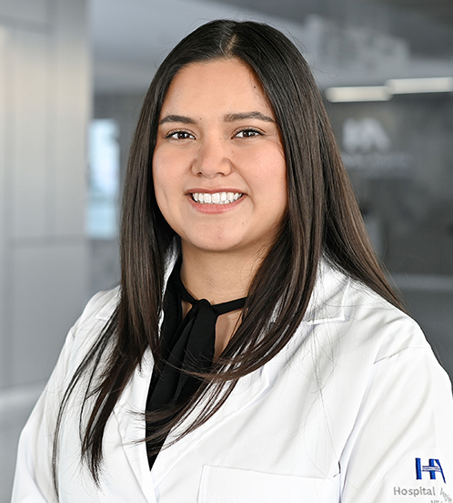 Es la foto de perfil de una odontopediatra en Querétaro de Hospital Angeles Centro-sur. Tiene el cabello lacio y en capas de color café oscuro. Usa una bata blanca y una blusa negra. Tiene los ojos café y está sonriendo.