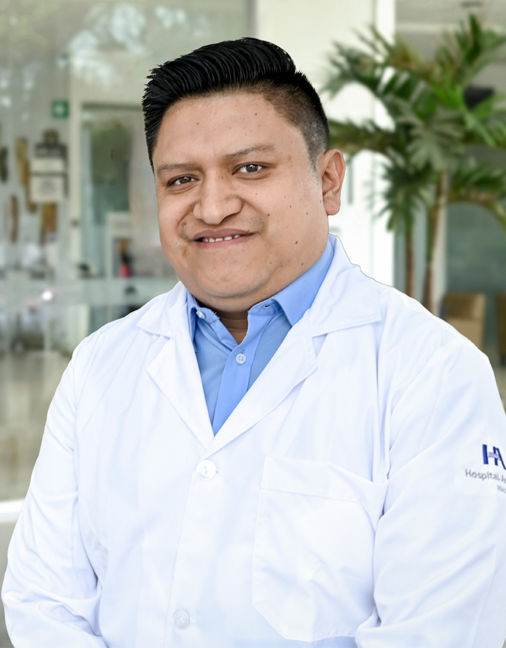 Es la foto de perfil de un radiooncólogo en Ciudad de México de Hospital Angeles Acoxpa. ES una persona robusta y usa una bata blanca con una camisa color azul claro.
