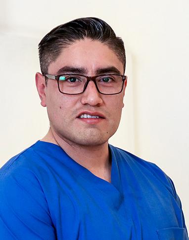 Es la foto de perfil de un cirujano oncológico en León de Hospital Angeles León. Utiliza un uniforme azul y lentes.