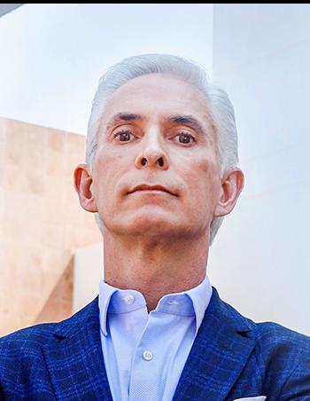 Es la foto de perfil de un cirujano plástico en Guadalajara de Hospital Angeles Del Carmen. Utiliza un saco azul marino y una camisa azul cielo, su cabello es canoso.