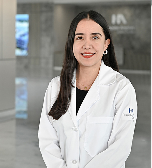 Es la foto de perfil de un cirujano general en Querétaro de Hospital Angeles Centro Sur. Usa una bata blanca, tiene una blusa negra, cabello oscuro y largo.