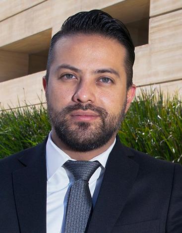 Es la foto de perfil de un cirujano maxilofacial en Ciudad de México de Hospital Angeles. Viste un traje negro con corbata negra y camisa blanca, tiene barba y ojos claros.