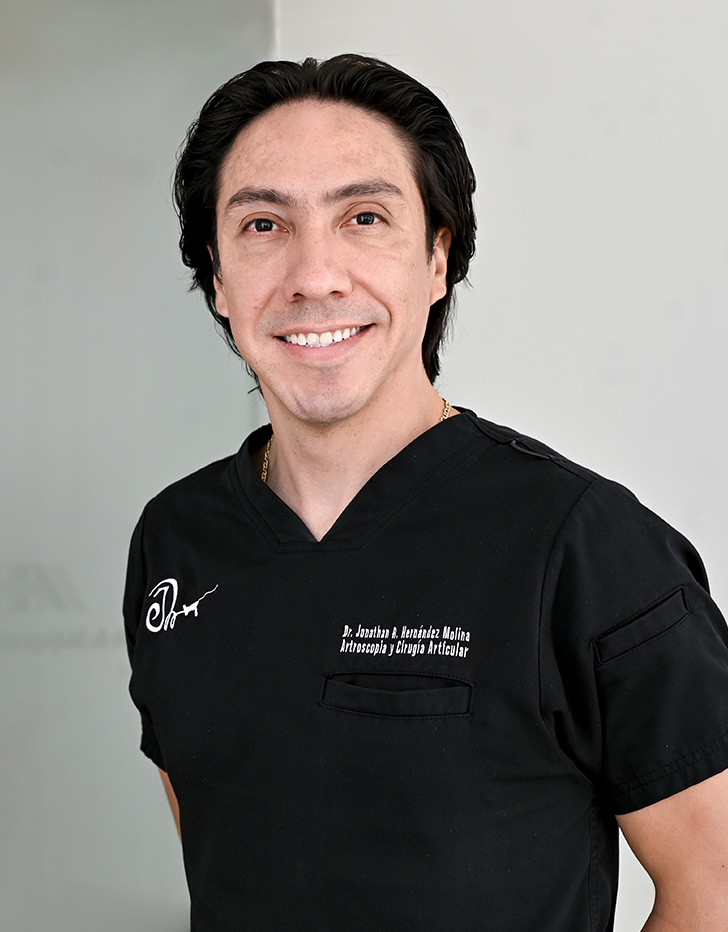 Es la foto de perfil de un ortopedista y traumatólogo en Ciudad de México de Hospital Angeles Universidad. Usa un uniforme médico color azul. Tiene el cabello color café oscuro. Está sonriendo.