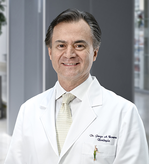 Es la foto de perfil de un urólogo en Huixquilucan de Hospital Angeles Lomas. El doctor tiene un saco beige, camisa azul claro y rayas verticales azul marino, la corbata es azul con puntos blancos. Tiene el cabello un poco largo.