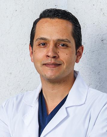 Es la foto de perfil de un cardiólogo intervencionista en León de Hospital Angeles León. Utiliza una bata blanca, un uniforme azul marino y está sonriendo.