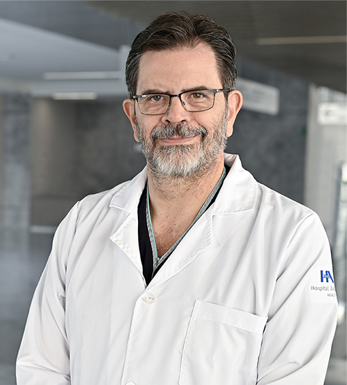 Es la foto de perfil de un anestesiólogo en Querétaro de Hospital Angeles Centro Sur. Usa un uniforme negro con cuello en V, el cual es de color gris, tiene lentes y cabello oscuro.