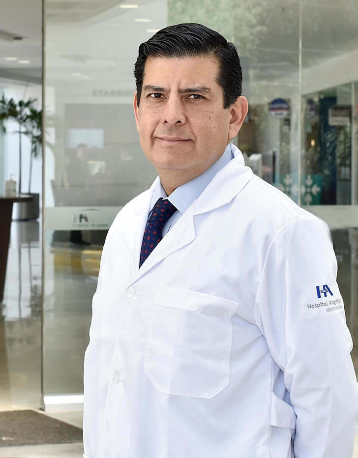 Es la foto de perfil de una cirujano oncológico pediátrico especialista en cirugía pediátrica en Ciudad de México de Hospital Angeles. Usa un traje negro, camisa blanca con cuadros pequeños y corbata verde con rayas azules claro y azul marino. 