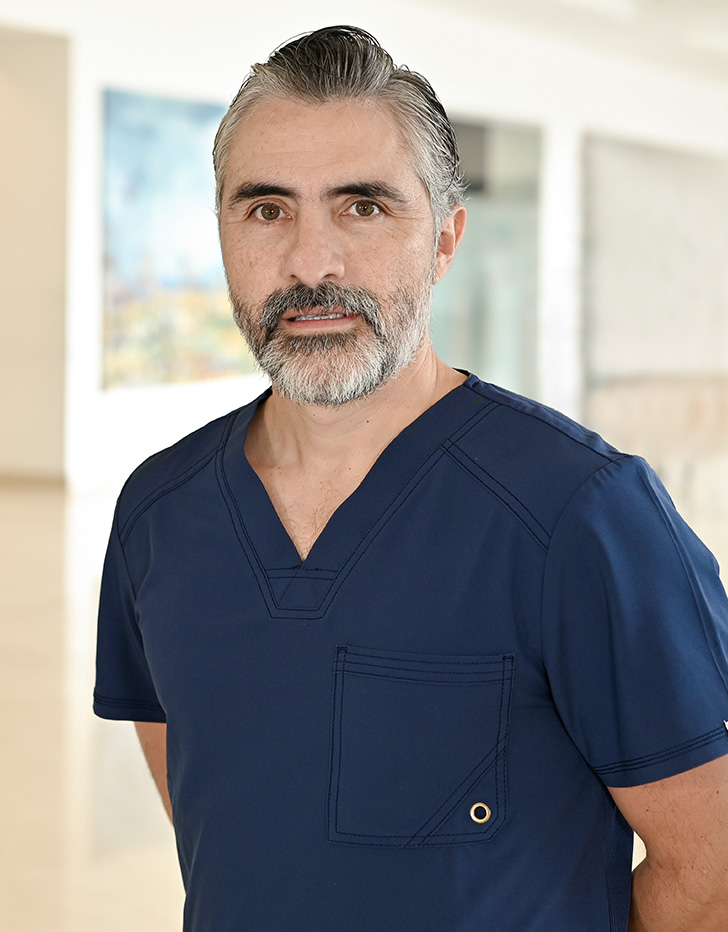 Es la foto de perfil de un pediatra en Xalapa de Hospital Angeles Xalapa. Usa un iniforme médico de color gris. Tiene la barba y cabello gris y negro.