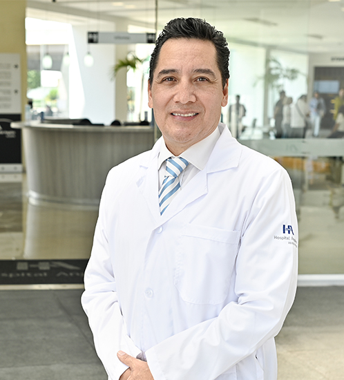 Es la foto de perfil de un ginecólogo y obstetra en Ciudad de México de Hospital Angeles Acoxpa. Usa una bata blanca con una camisa blanca y una corbata de rayas azul y blanco. Tiene el cabello negro.