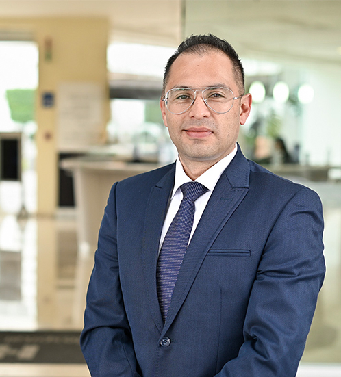 Es la foto de perfil de un oncólogo médico en Ciudad de México de Hospital Angeles Acoxpa. Usa un traje azul con una camisa blanca y una corbata azul con detalles blancos. Usa lentes de gota color plata.