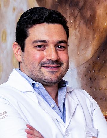 Es la foto de perfil de un oftalmólogo en León de Hospital Angeles León. Utiliza una bata blanca, una camisa azul claro y tiene el cabello negro.