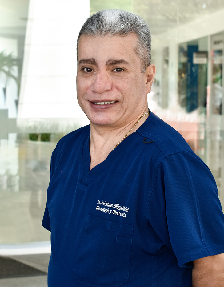 Es la foto de perfil de un ginecólogo y obstetra en Ciudad de México de Hospital Angeles. El doctor viste un uniforme gris, tiene el cabello canoso y está sonriendo.