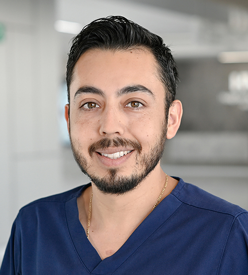Es la foto de perfil de un cirujano general en Querétaro de Hospital Angeles Centro Sur. está usando un uniforme azul marino, tiene una cadena dorada, barba y bigote y cejas pobladas.