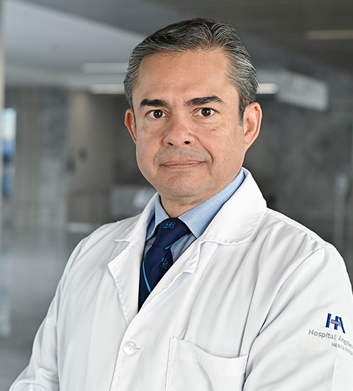 Es la foto de perfil de un cirujano pediátrico en Querétaro de Hospital Angeles Centro Sur. Utiliza un traje azul y una camisa negra, tiene cejas pobladas y cabello canoso.