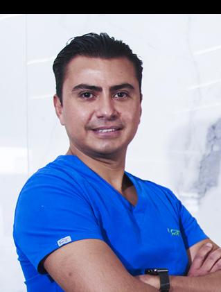 Es la foto de perfil de un pediatra y neonatólogo en Ciudad de México de Hospital Angeles Santa Mónica. Usa un iniforme médico azul. Tiene el cabello negro y los brazos cruzados.