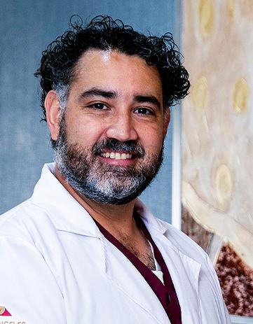 Es la foto de perfil de un anestesiólogo y alergólogo en León de Hospital Angeles León. Usa una bata blanca, tiene el cabello rizado y barba canosa. 