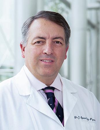 Es la foto de perfil de un cirujano general en Huixquilucan de Hospital Angeles Lomas. Usa una bata blanca, corbata negra con rosa y camisa blanca.