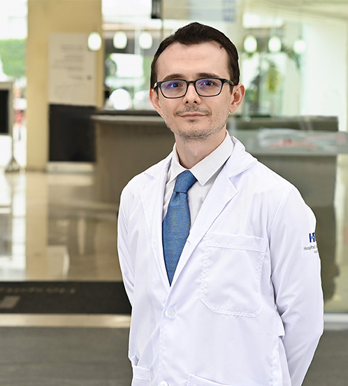 Es la foto de perfil de un endocrinólogo en Ciudad de México de Hospital Angeles Acoxpa. Usa una bata y camisa blanca con una corbata azul. Tiene el cabello café y usa lentes cuadrados.