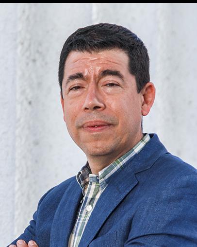 Es la foto de perfil de un oncólogo médico en León de Hospital Angeles León. Usa un saco azul marino, camisa y tiene cabello oscuro y cejas pobladas.